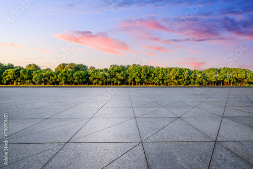 Empty square floor and green trees with sky clouds at sunset