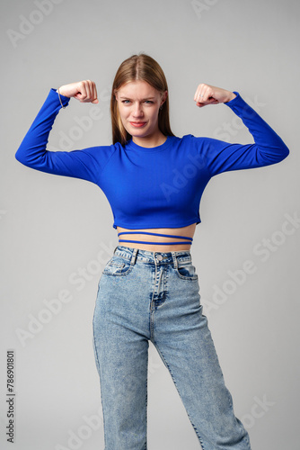 Smiling Young Woman in Blue Top Celebrating Success With Raised Fist