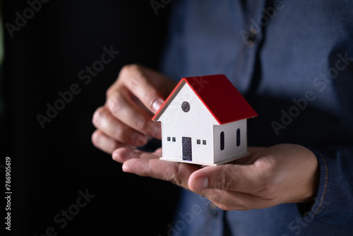 Man hand holding a house model in his hand,The concept of owning a house or mortgaging real estate.