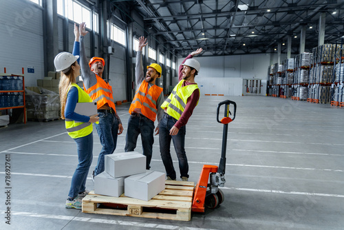 Confident team, managers, engineers wearing hard hats, work wear and vests working in warehouse