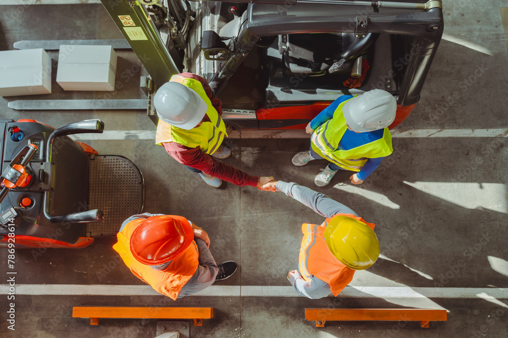 Group of successful managers, engineers wearing hard hats, workwear and vests shaking hands Group of successful managers, engineers wearing hard hats, workwear and vests shaking hands