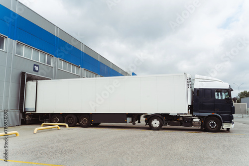 Truck parked near cargo terminal, loading goods on street near warehouse. Concept of transportation