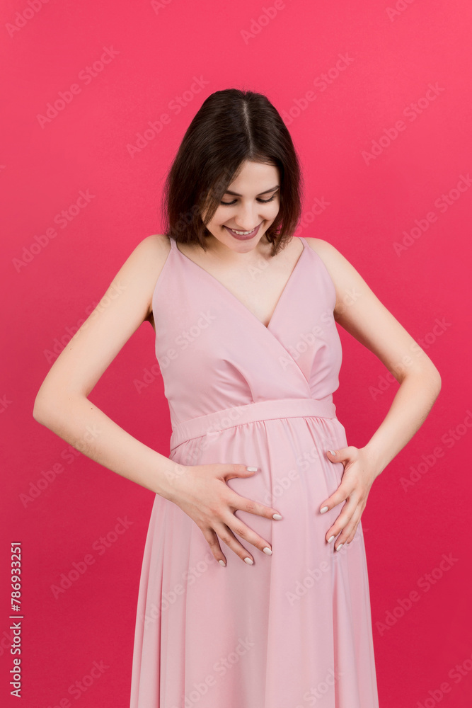 Happy pregnant woman touching her abdomen at Colored background. Future mother. Expecting of a baby. Copy space Happy pregnant woman touching her abdomen at Colored background. Future mother. Expecting of a baby. Copy space