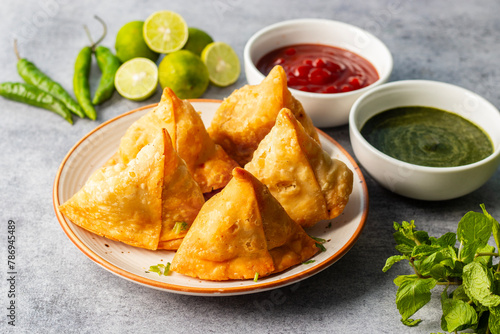 selective focus Samosa, Spiced potato-filled pastry, crispy, Savory, popular Indian snack with tomato and mint chutney. 