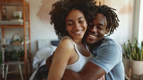 Young couple is excitedly hugging at home, celebrating the positive result of a pregnancy test.