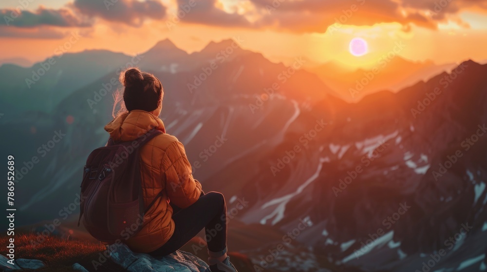 A woman sitting on top of a mountain watching the sun set. Suitable for travel and nature concepts