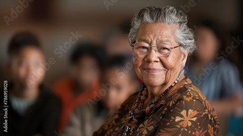 A close-up portrait of a smiling elderly woman with glasses and a traditional necklace, exuding wisdom and warmth.