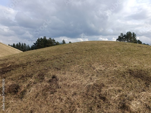 Salduve hill during cloudy day. Small hill. Grass is growing on hill. Staircase leading to the top. Cloudy day with white and gray clouds in sky. Nature. Salduves piliakalnis. photo