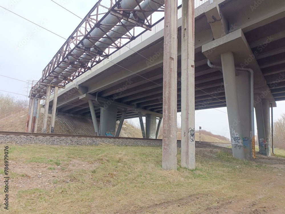 Two way railroad tracks and concrete bridge in countryside. Two railway tracks. Cloudy day. Countryside. Fields and trees. Two way railroad tracks and concrete bridge in countryside. Two railway tracks. Cloudy day. Countryside. Fields and trees.