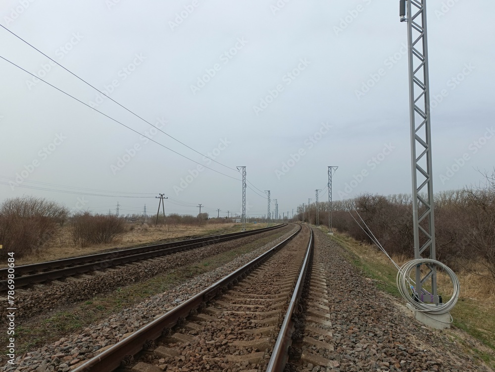 Two way railroad tracks in countryside. Two railway tracks. Cloudy day. Countryside. Fields and trees.