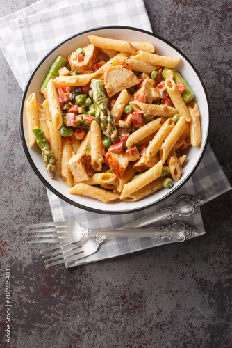 Mexican Creamy Chicken Chipotle Pasta with vegetables closeup in the bowl on the table. Vertical top view from above