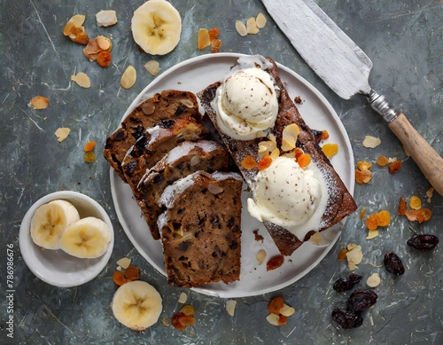 Zenith view of a chocolate banana bread slices with vanilla ice cream. A dessert knife and banana slices at side.