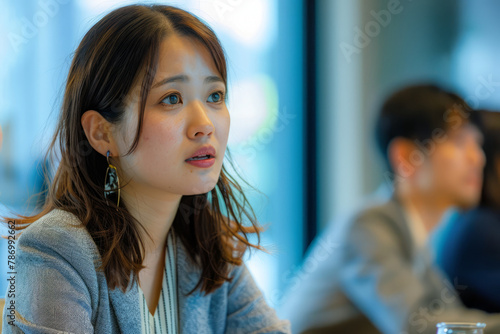 A Japanese businesswoman participates actively in a meeting, listening to discussions with focus.