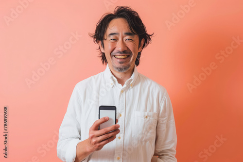 A Japanese man smiles brightly while recommending a vibrant mobile app on a peach background, his positive energy contagious. © AI_images