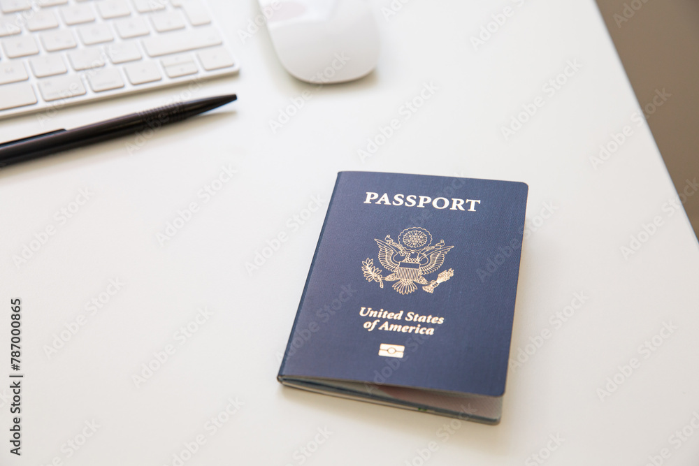 Close up of an American passport on white table, with a pan, a computer keyboard and mouse Close up of an American passport on white table, with a pan, a computer keyboard and mouse