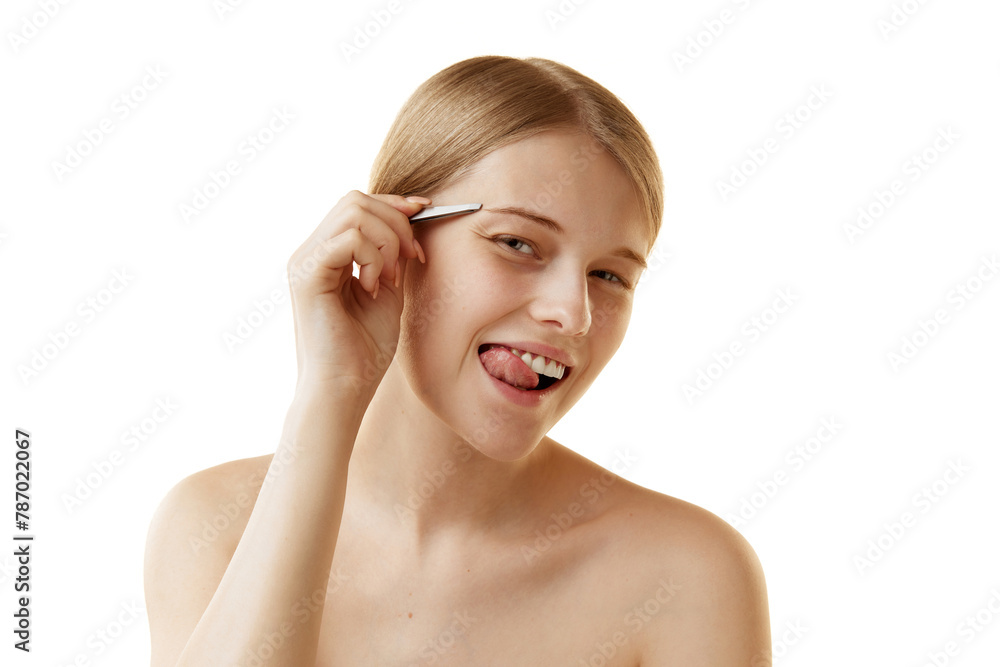Young attractive woman looking at camera and grimacing while hold tweezers near eyebrows against white studio background. Concept of natural beauty, organic cosmetic, spa procedures, face-care. Young attractive woman looking at camera and grimacing while hold tweezers near eyebrows against white studio background. Concept of natural beauty, organic cosmetic, spa procedures, face-care.