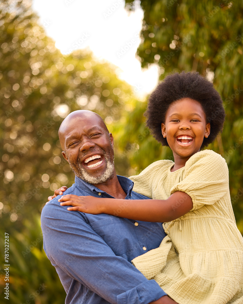Obraz premium Portrait Of Loving Grandfather Laughing And Hugging Granddaughter Outdoors In Countryside Or Garden