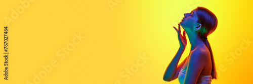 Banner. Side view photo of young woman massaging her neck and chin to prevent double chin in neon light against gradient background. Concept of beauty, organic cosmetic, spa procedures, face-care.