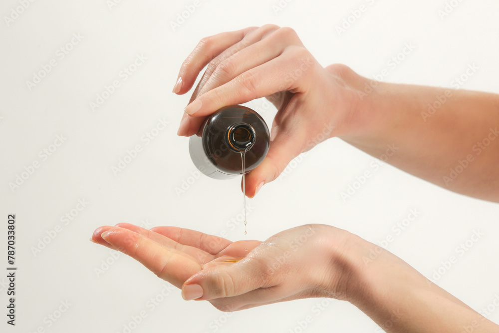 The masseur pours oil from the bowl on her hand The masseur pours oil from the bowl on her hand