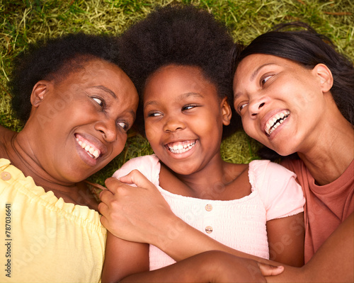 Looking Down On Three Generation Female Family Laughing And Lying On Grass Outdoors In Countryside