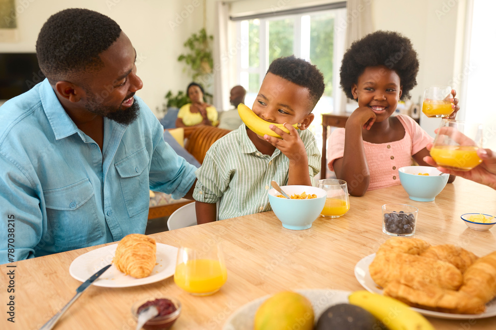 Son Having Fun Playing With Banana As Family Sit At Kitchen Counter Eating Breakfast At Home Son Having Fun Playing With Banana As Family Sit At Kitchen Counter Eating Breakfast At Home