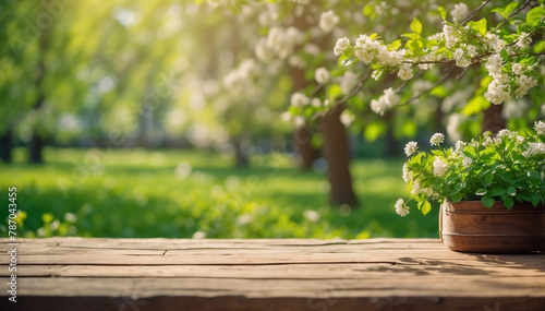 Blurred Spring background with green lush foliage and flowering branches with an empty wooden table  