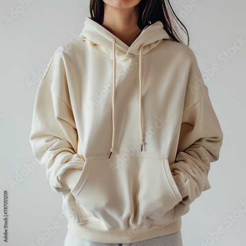 The girl is wearing a beige plain oversized hoodie. Women's sweatshirt close-up.