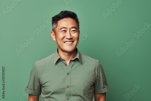 Portrait of a blissful asian man in his 40s donning a trendy cropped top isolated in pastel green background