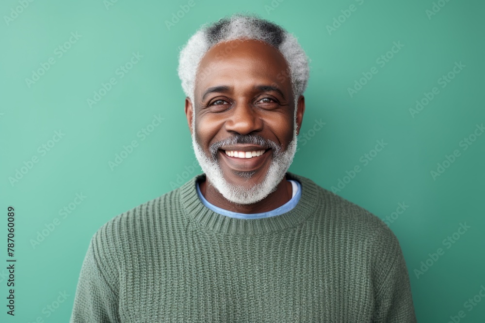 Portrait of a grinning afro-american man in his 50s wearing a cozy sweater in front of pastel green background Portrait of a grinning afro-american man in his 50s wearing a cozy sweater in front of pastel green background