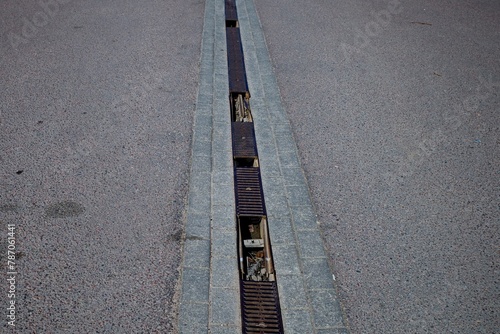 A road with three types of road surface with asphalt paving stones, tiles and a gutter with rainwater drainage.