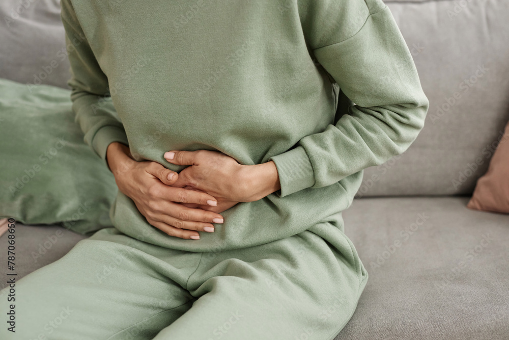 Close up of unrecognizable woman holding onto stomach suffering from period cramps or pains copy space Close up of unrecognizable woman holding onto stomach suffering from period cramps or pains copy space