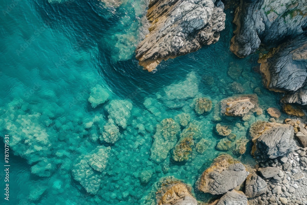 This photo captures an aerial view of a body of water with rocks surrounding it, Aerial perspective of a rocky coastline with clear, calm waters, AI Generated