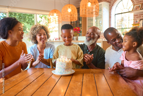 Multi-Generation Family Celebrating Grandson's Birthday At Home Blowing Out Candles On Cake