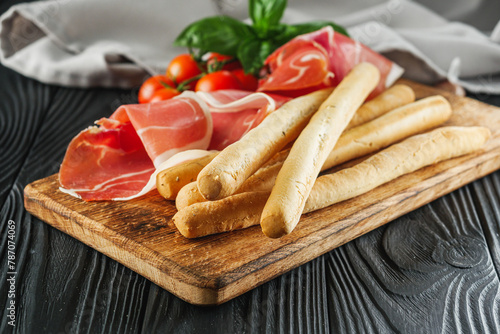 crispy grisini with prosciutto on a black wooden rustic background photo