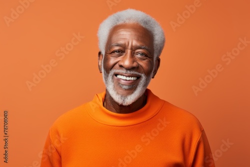 Portrait of a grinning afro-american man in his 80s wearing a thermal fleece pullover over soft orange background