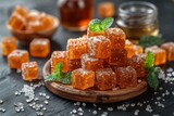 Vibrant, glistening candied fruit jelly cubes garnished with fresh mint on a wooden plate with sugar crystals scattered around