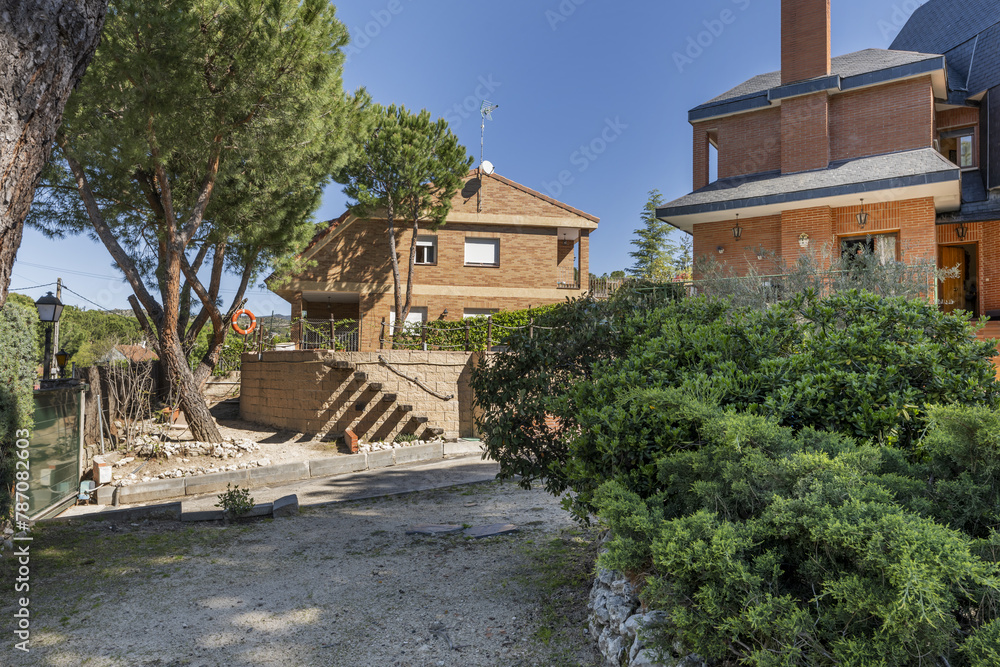 Estate with sandy paths, chalet with characteristic black slate tile roof, hedges and abundant trees
