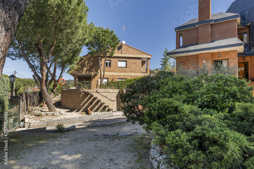 Estate with sandy paths, chalet with characteristic black slate tile roof, hedges and abundant trees