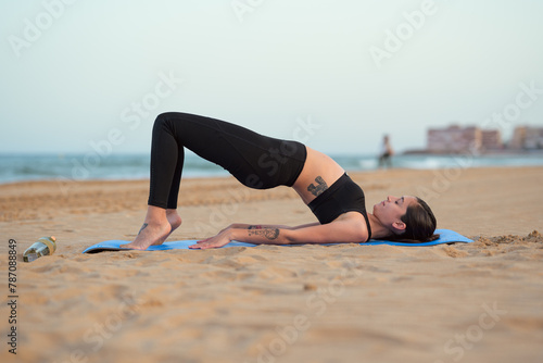 Woman in sports wear top practicing yoga on beach