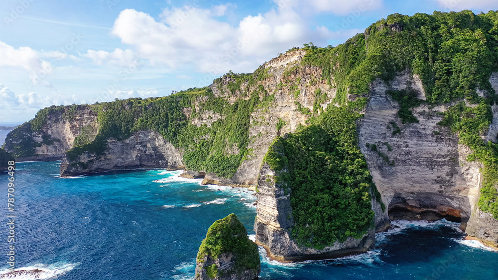 Nusa Penida, Indonesia. Rocky area, covered with vegetation, washed by turquoise sea. Travel concept.
