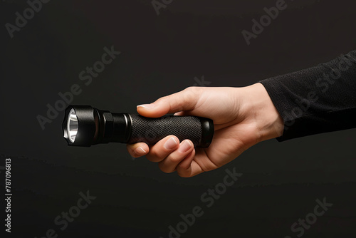 Black flashlight in woman's hand isolated on black background
