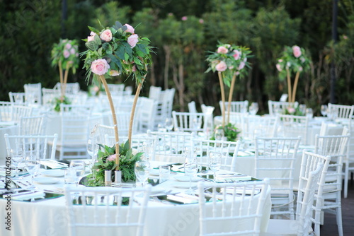 Elegant outdoor wedding reception with round tables, white chairs, and floral centerpieces