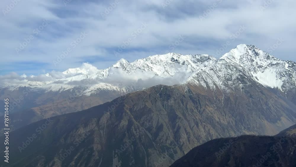 Archonsky Pass. The pass connects the Kurtatinsky gorge with the Alagirsky. Alanya, view of the mountains of the North Caucasus, peaks covered with snow. Sunny day, blue sky with a slight haze. 4К Archonsky Pass. The pass connects the Kurtatinsky gorge with the Alagirsky. Alanya, view of the mountains of the North Caucasus, peaks covered with snow. Sunny day, blue sky with a slight haze. 4К