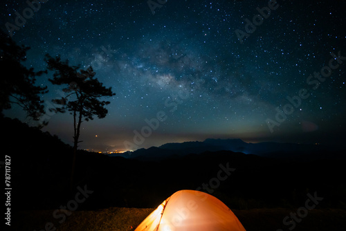 nature traveling with orange camping tent on mountain with milky way background