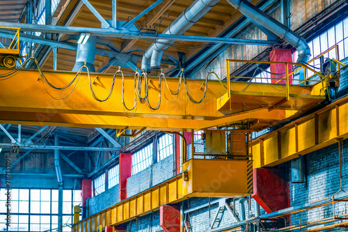 Yellow metal cargo beam with crane in selective focus. Inside the metal structures production workshop. Industrial steel production. Copy space.