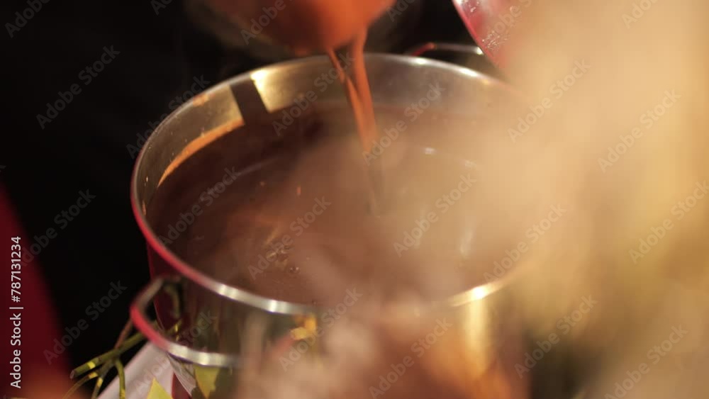 Girl stirs cocoa in a saucepan with a ladle, the melted chocolate stirred in Girl stirs cocoa in a saucepan with a ladle, the melted chocolate stirred in