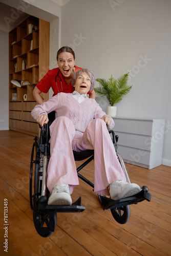 Crazy woman caregiver riding fast elderly woman patient on wheelchair © Nomad_Soul