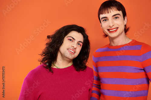 handsome stylish jolly gay friends in vibrant clothes posing happily together, pride month photo