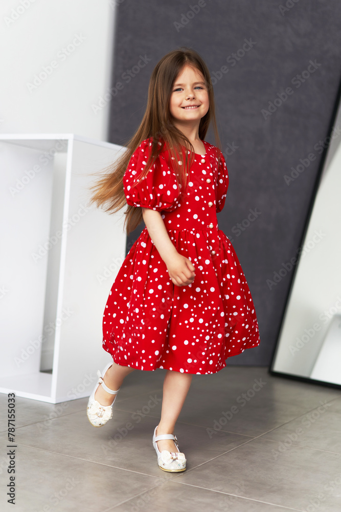 Beautiful little girl with long hair, wearing a colorful spring dress in flowers Beautiful little girl with long hair, wearing a colorful spring dress in flowers
