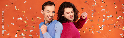 jolly handsome friends in stylish clothes with makeup posing under confetti rain, pride, banner photo